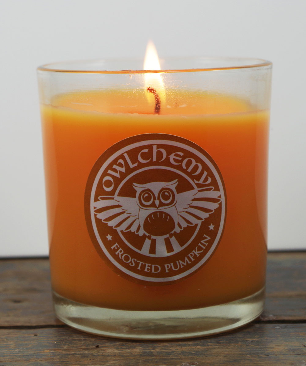 An orange Spiced Pumpkin candle with a lit flame  