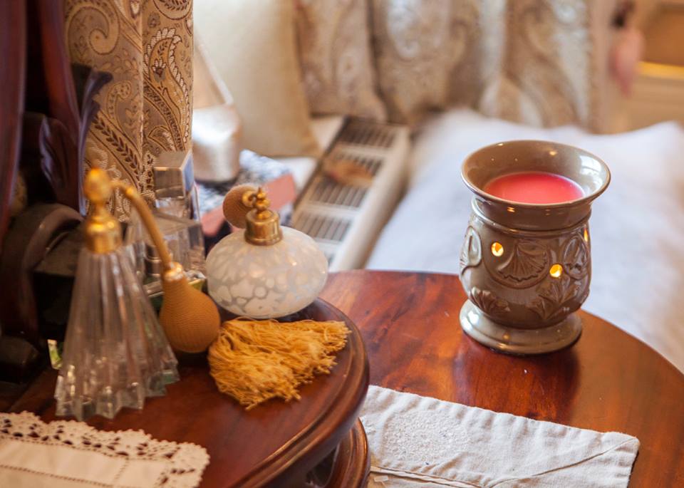Our Morning Glory Wax Warmer lit on a wooden dressing table next to some perfume