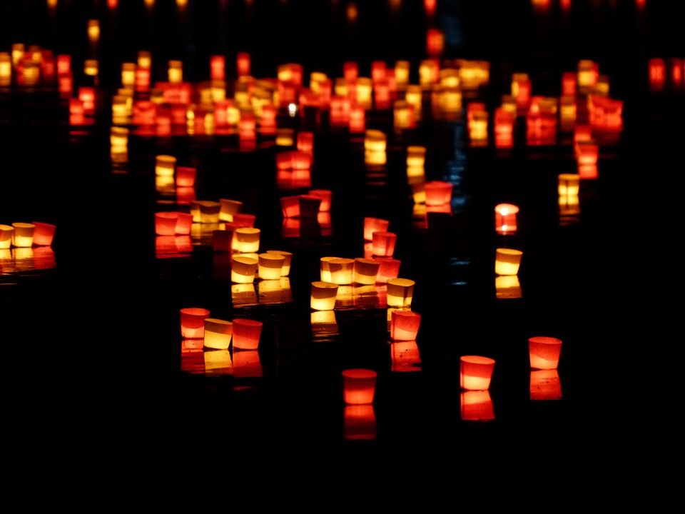 Little red, orange and yellow candles floating on a river 