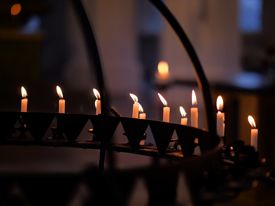 A metal candelabra with a multitude of candles burning inside it.