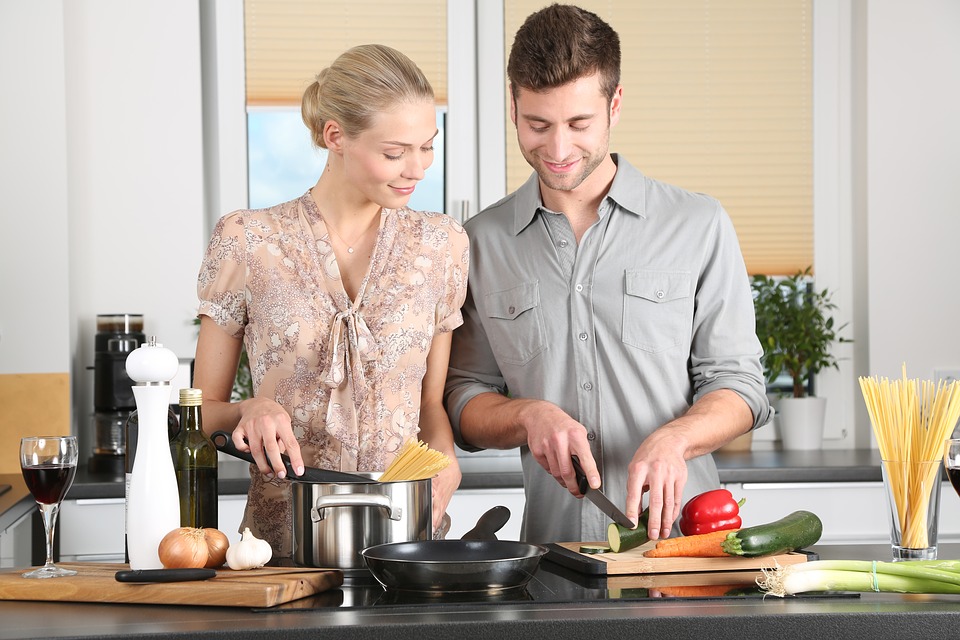 A woman and man preparing food together at a cookery class. 