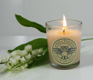 Our luxury Lily of the Valley scented candle next to a white flower.