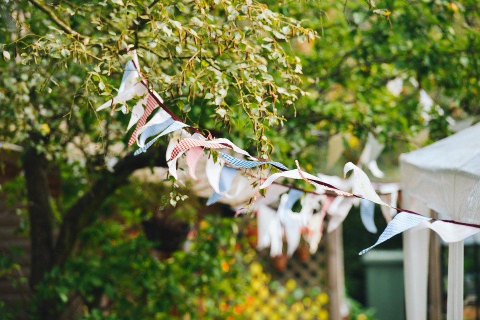 Some multicoloured patchwork bunting hung in a garden blowing in the wind.