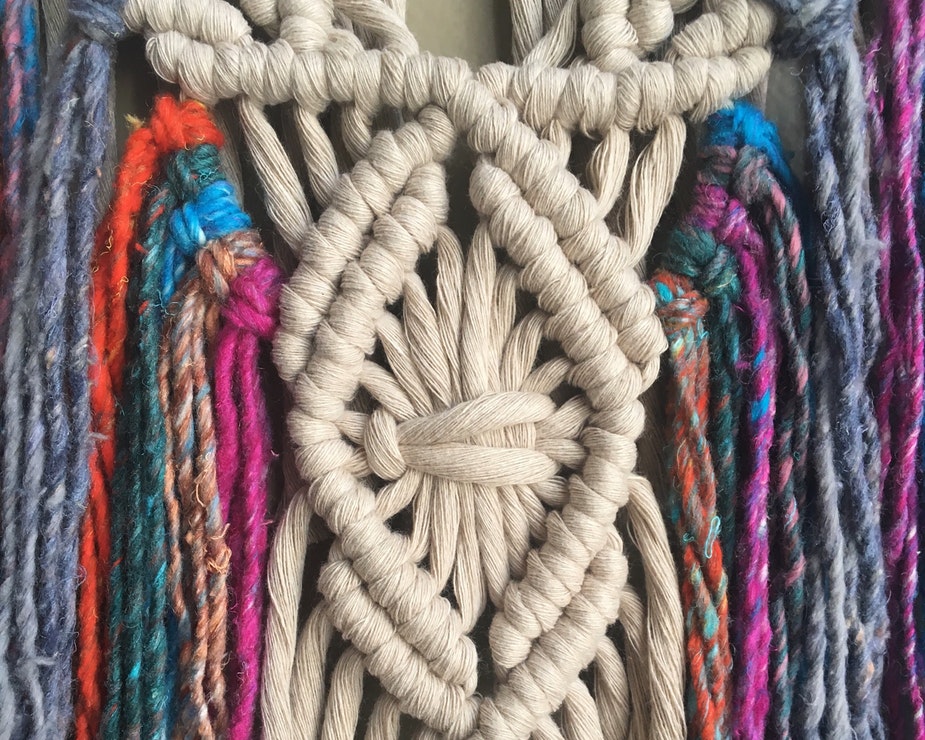 A multicoloured macramé wall hanging with a large diamond knot in the centre.